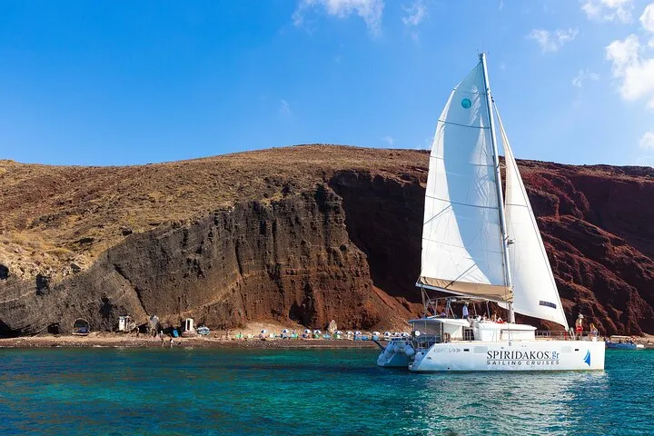 Catamaran deck with swimmers near White Beach on a classic Santorini catamaran cruise, Santorini Greece