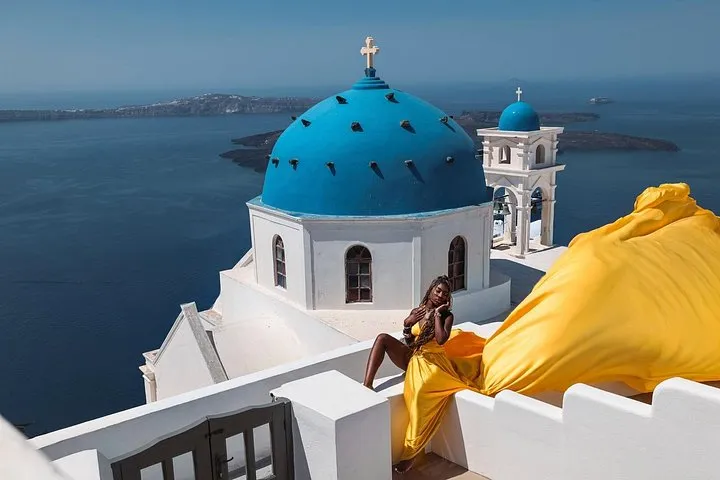Long flowing dress against a blue dome on a Santorini flying dress photoshoot, Santorini Greece